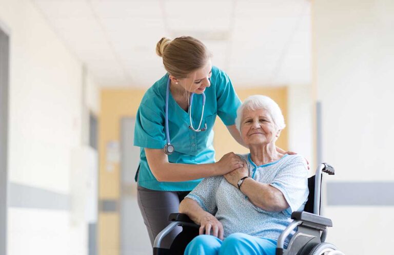 A group of seniors seated at a communal table engaging in a guided activity with a caregiver.